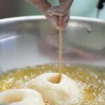 Close-up of homemade donuts being fried in a kitchen setting in Indonesia.